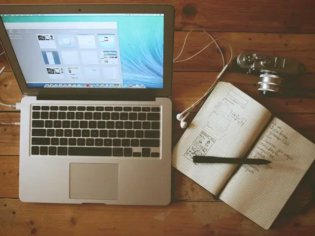 A notebook, camera and laptop on a creative desk